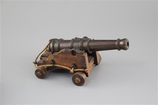 An early 20th century bronze model of a Naval cannon, on wooden trunnion base, length 25cm